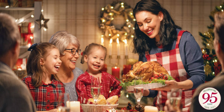 Family gathering around the dinner table with a turkey at holiday time